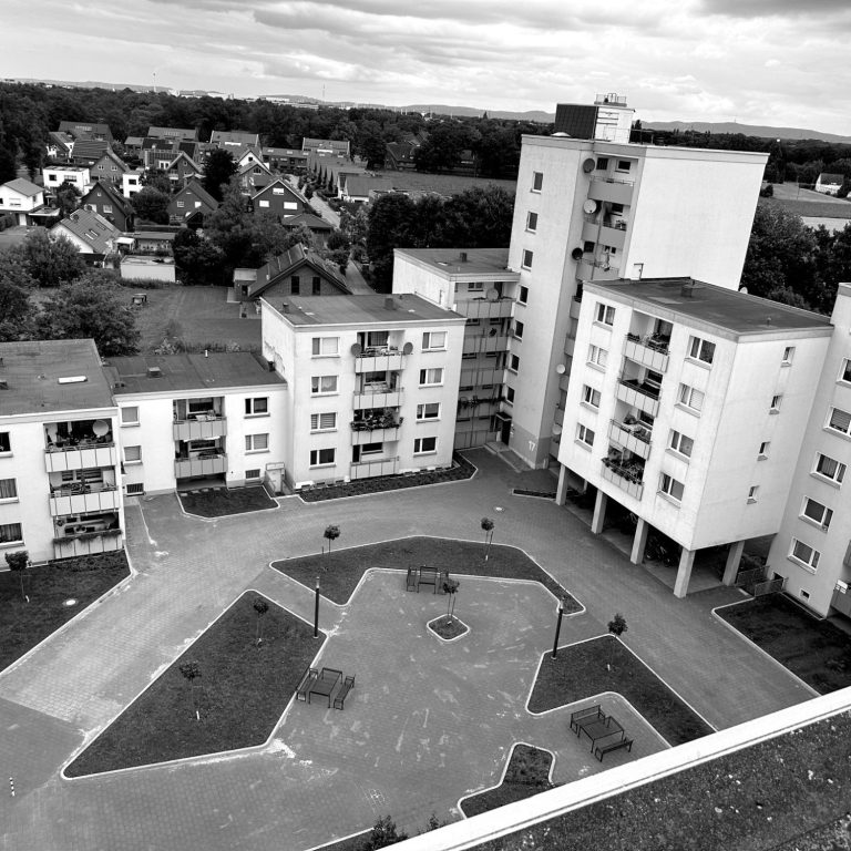 Innenhof und Fassade einer Wohnanlage in Gütersloh. Blick auf ein modernes Wohngebäude mit Innenhof in Schwarz-Weiß.