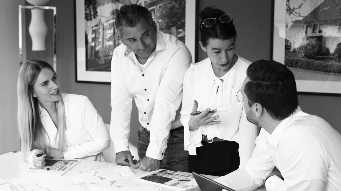 Unser Team der Handwerksbau AG Vier Personen stehen um einen Computerbildschirm und lächeln.